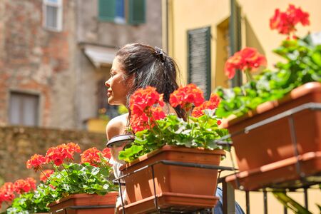 Portrait of smiling elegant tourist woman in long dress and straw hat in old Europe town rejoicingの写真素材