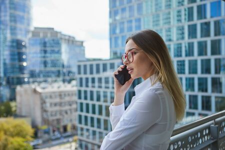Real estate agent talking on the phone. in the background modern buildings, office buildingsの写真素材
