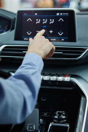 the driver controls the air conditioning in a modern electric carの写真素材