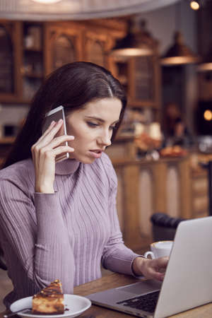 Woman works remotely online from cafe while quarantine coronavirus is in effect. Concept of checking mail, blogger, freelancerの写真素材