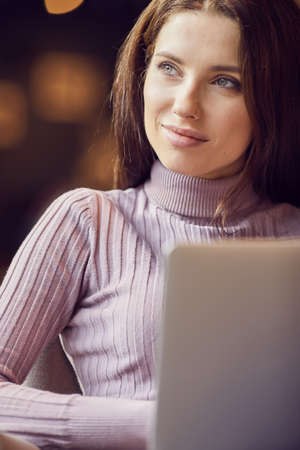 Woman works remotely online from cafe while quarantine coronavirus is in effect. Concept of checking mail, blogger, freelancerの写真素材