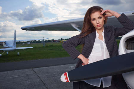 Beautiful successful caucasian young lady wearing stylish suit in private aircraft. Business, success, travel concept.の写真素材