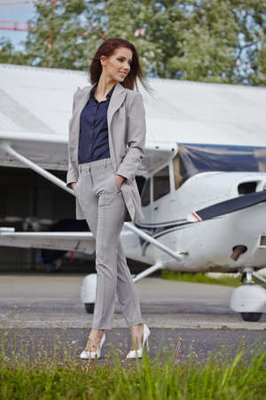 Beautiful young businesswoman standing outdoors near small private aircraftの写真素材