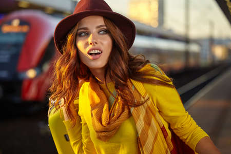 A woman with yellow travel suitcases is waiting for a train at the train stationの写真素材