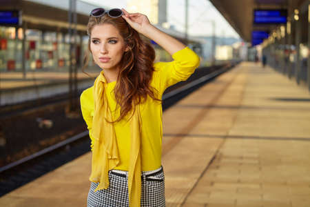 A woman with yellow travel suitcases is waiting for a train at the train stationの写真素材