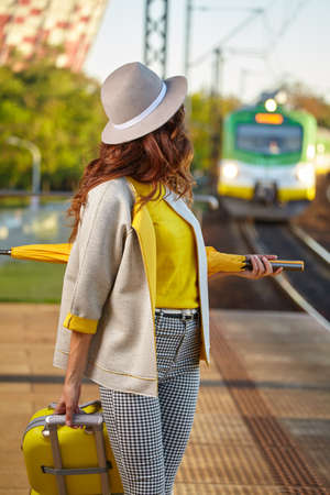 A woman with yellow travel suitcases is waiting for a train at the train stationの写真素材