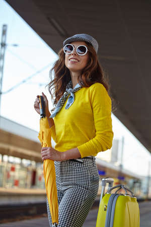 A woman with yellow travel suitcases is waiting for a train at the train stationの写真素材