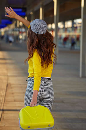 A woman with yellow travel suitcases is waiting for a train at the train stationの写真素材
