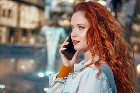 Young Caucasian woman texting cell phone in city at nightの写真素材