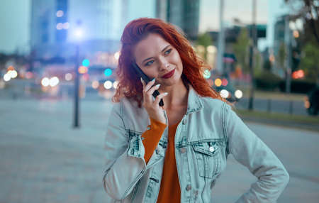 Young Caucasian woman texting cell phone in city at nightの写真素材