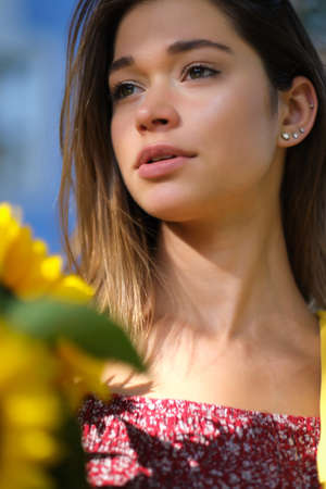 Young happy beautiful girl is walking in dress with a bouquet of sunflowers on a city street. Autumn...