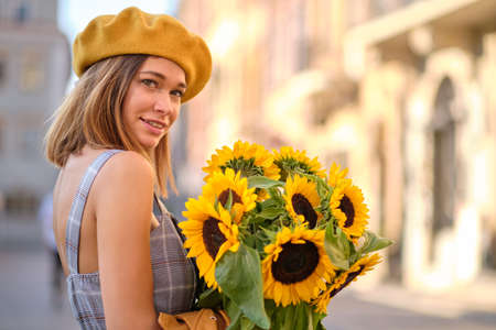 Young fashion woman with a bouquet of sunflowers in the cityの写真素材