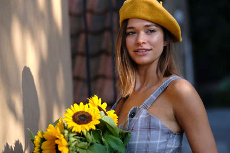 Young fashion woman with a bouquet of sunflowers in the cityの写真素材