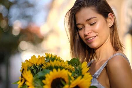 Young fashion woman with a bouquet of sunflowers in the cityの写真素材