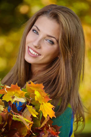 Beautiful elegant woman standing in a park in autumnの写真素材