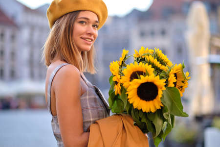 Young fashion woman with a bouquet of sunflowers in the cityの写真素材