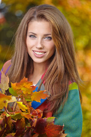Beautiful elegant woman standing in a park in autumnの写真素材