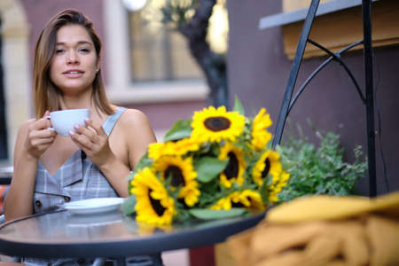 Young woman drinking coffee in a cafe on the street of the old cityの写真素材