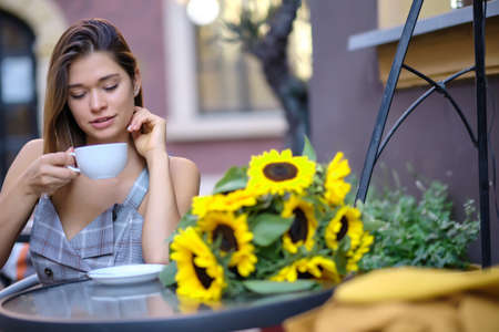 Young woman drinking coffee in a cafe on the street of the old cityの写真素材
