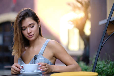 Young woman drinking coffee in a cafe on the street of the old cityの写真素材