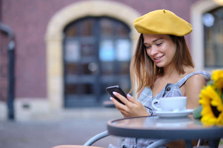 A woman uses a smartphone in a cafe on the street of the old cityの写真素材