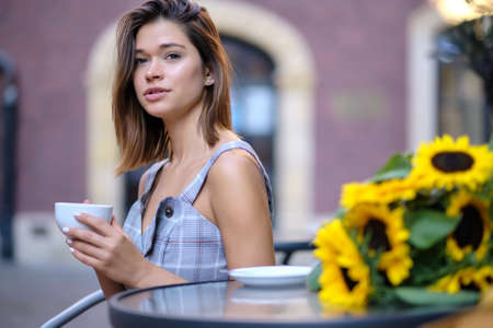 Young woman drinking coffee in a cafe on the street of the old cityの写真素材