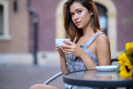 Young woman drinking coffee in a cafe on the street of the old cityの写真素材