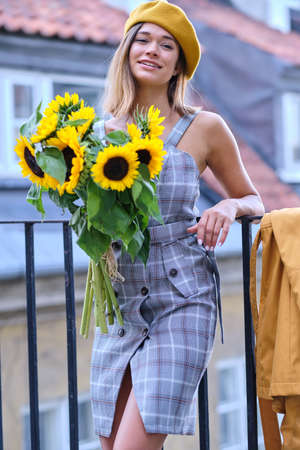 Street portrait of a beautiful young woman holding a sunflowerの写真素材