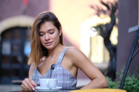 young stylish woman sitting in cafe, holding drinking cup cappuccinoの写真素材