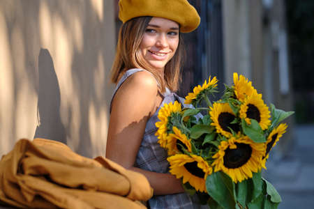 Street portrait of a beautiful young woman holding a sunflowerの写真素材