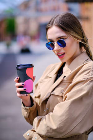 Woman with a cup of coffee on the street of an industrial cityの写真素材