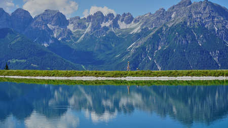 A tourist on a walk with a dog on the shores of a mountain lakeの写真素材