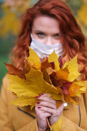 A young woman protecting from corona virus when walking in park. Autumn background.の写真素材