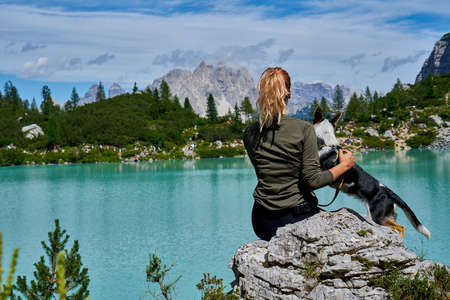 a young woman and her dog hiking to the top of a mountain. Pandemic covid isolationの写真素材