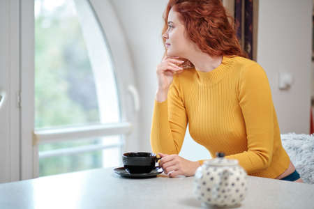 Young woman at home sipping tea from a cupの写真素材