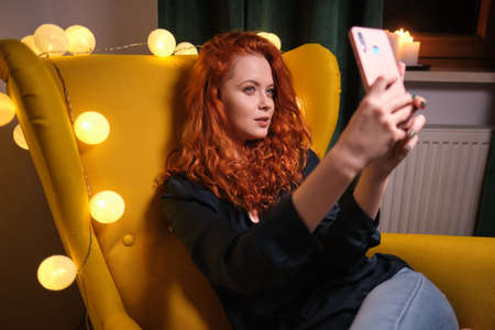 Pretty girl using her smartphone on couch at home in the living room
