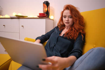 Redhead young woman using laptop at home. covid isolation. home officeの写真素材