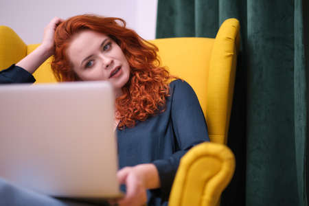 Redhead young woman using laptop at home. covid isolation. home officeの写真素材