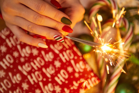Festive decorations and sparklers in the hand of a womanの写真素材