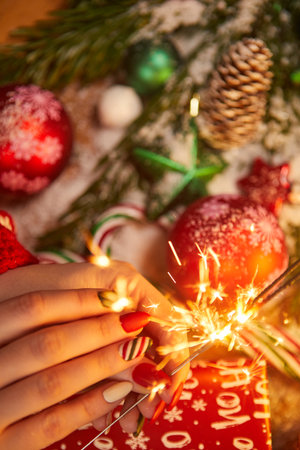 Festive decorations and sparklers in the hand of a womanの写真素材
