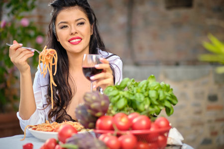 country life. An Italian woman eats dinner and pasta in her home gardenの写真素材