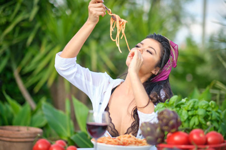 country life. An Italian woman eats dinner and pasta in her home gardenの写真素材