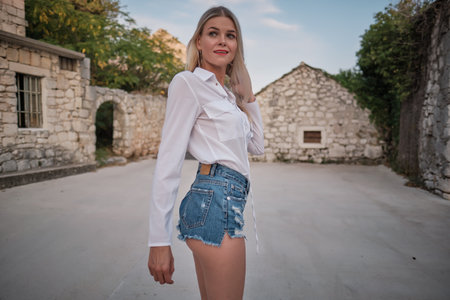 Traveling by Europe. Happy young woman in elegant dress walking by streets, Croatia.の写真素材