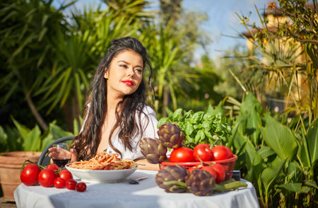 country life. An Italian woman eats dinner and pasta in her home gardenの写真素材