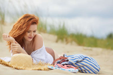 Beautiful redhead woman at a beach smilingの写真素材