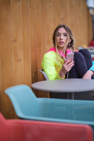 Fitness runner on mobile smart phone app tracking progress listening to music with earphones for fitness motivation. runner in sportswear relaxing sitting getting inspired.の写真素材