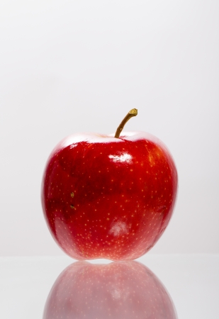 Single red apple on glass surfaceの写真素材