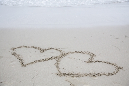 Two hearts carved into wet sandの写真素材