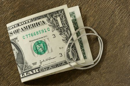 Dollar bill and rubber ring over dark wooden backgroundの写真素材