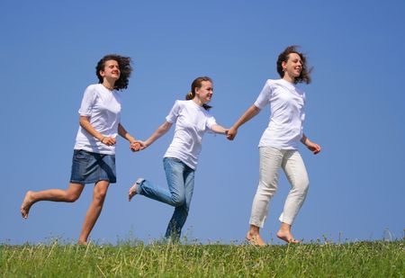 Three beautiful girls run against a blue skyの写真素材